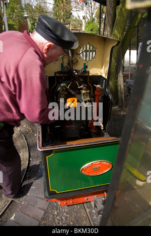 Conducteur d'un modèle miniature à voie étroite de chemin de fer locomotive train vapeur chaudière alimente dans un centre de jardinage, Poynton. Cheshire. UK Banque D'Images