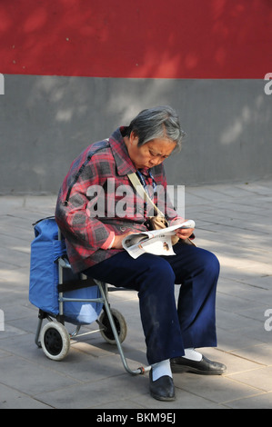 Femme plus âgée lisant le parc Beihai Beijing Chine Banque D'Images