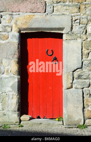 La porte rouge vif dans la basse-cour, avec lucky horseshoe Banque D'Images