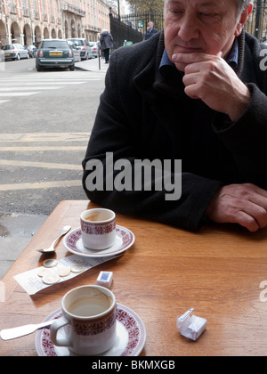 Homme mature assis devant un café à Paris Banque D'Images