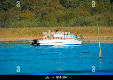 L'homme le soleil sur un petit bateau de plaisance l'ancrage sur un lac près de Müritz, Western-Pomerania Meckenburg, Allemagne Banque D'Images