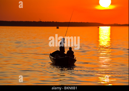 Silhouette de deux pêcheurs en bateau de pêche, plage Kolpinsee, coucher et au lever du soleil, 102, Muritz, Mecklembourg Western-Pommerania Banque D'Images