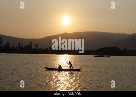 Un couple dans un bateau à rames sur la rivière à Kampot, Cambodge au coucher du soleil Banque D'Images