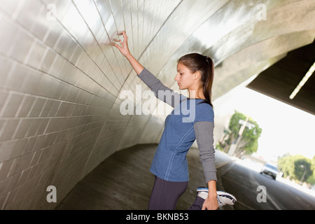 Hispanic woman stretching en tunnel urbain Banque D'Images