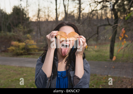 Caucasian woman ludique avec des feuilles couvrant ses yeux Banque D'Images