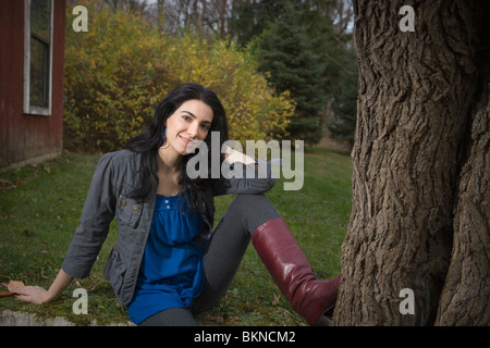 Caucasian woman sitting in tree près de Banque D'Images
