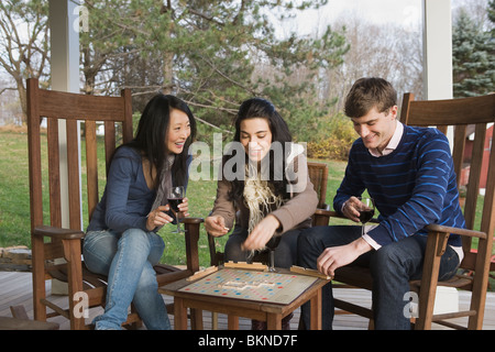 Les amis jouant au Scrabble on porch Banque D'Images