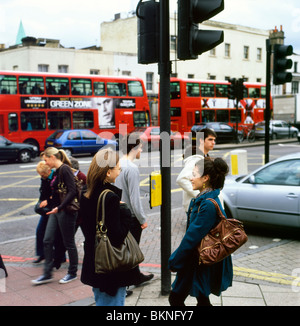 Les jeunes femmes en conversation sur une rue animée dans Islington avec bus rouge London England UK Banque D'Images