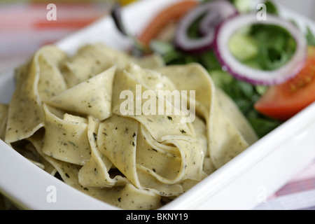 Végétarien fraîchement préparés ou cuits Pâtes Pappardelle avec un mélange de salade du jardin et basilic herbes dans un déjeuner bol avec aucun peuple Banque D'Images