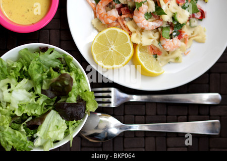 Fraîchement préparés et cuisinés italien ou un style méditerranéen régime alimentaire des crevettes fraîches et des pâtes servies avec une salade mixte avec aucun peuple Banque D'Images