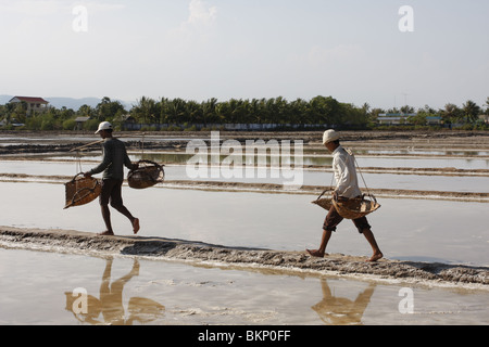 Hommes et femmes travaillent dans les exploitations de sel chaud scorchingly de Kampot, au Cambodge. Banque D'Images