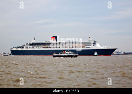 Bateau de croisière QUEEN MARY 2 visiter Liverpool avec remorqueurs assistant et traversée en ferry Mersey en face d'elle Banque D'Images