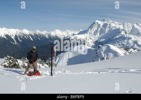 Un skieur d'arrière-pays de retirer peaux et la préparation au ski hors piste à la Washington Cascades avec le Mont Shuksan derrière. Banque D'Images