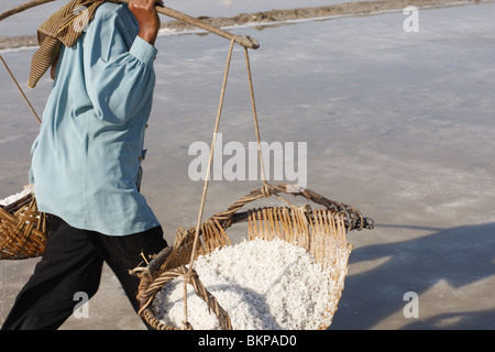 Une femme porte des paniers remplis de sel sur une ferme près de Kampot, Cambodge Banque D'Images