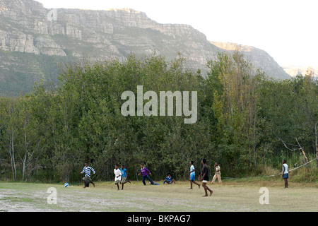 Les enfants africains jouant au football pieds nus dans un champ à Hout Bay, à Cape Town, Afrique du Sud. Banque D'Images