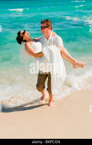 Akumal, Riviera Maya, Mexique ; un groom transportant la mariée sur la plage de Gran Bahia Principe Tulum All-Inclusive Resort Banque D'Images