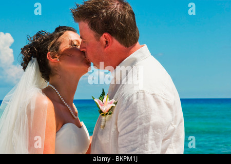 Akumal, Riviera Maya, Mexique ; une mariée et le Marié baiser sur la plage de Gran Bahia Principe Tulum All-Inclusive Resort Banque D'Images