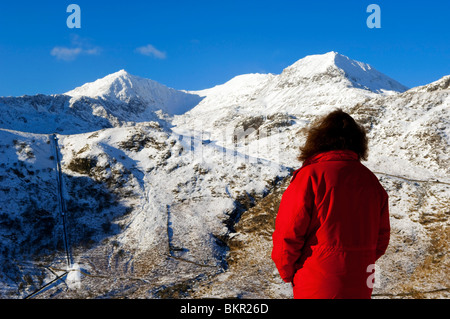 Pays de Galles, Gwynedd, Snowdonia. Un walker ressemble à l'ouest à dévaler les pentes enneigées de Snowdon. (MR) Banque D'Images