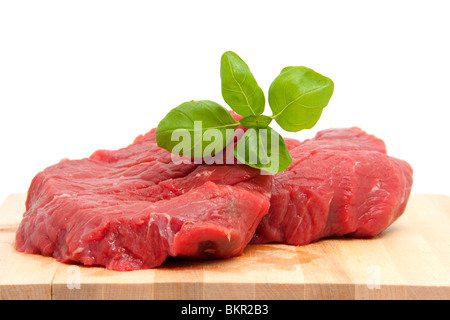 Steak cru sur une planche à découper sur fond blanc Banque D'Images