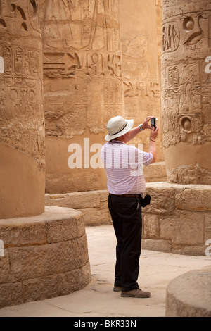 Egypte, Karnak. Un touriste photographie les colonnes en pierre massive dans la salle hypostyle. Banque D'Images