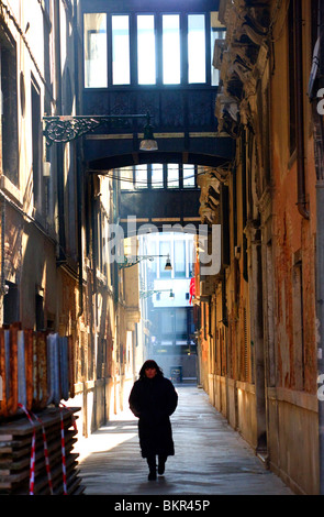 Italie, Vénétie, Venise ; une femme marchant le long d'une des nombreuses rues étroites menant à la Gran Canal. Banque D'Images