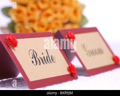 Mariée et le marié nom cartes sur une table de mariage avec bride's bouquet de roses jaunes à l'arrière-plan Banque D'Images