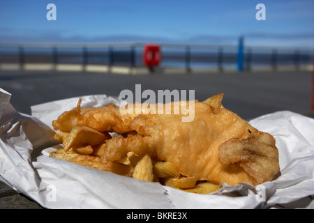 Anglais traditionnel fish and chips dans un papier sur l'enrubanneuse jetée à la mer england uk Banque D'Images