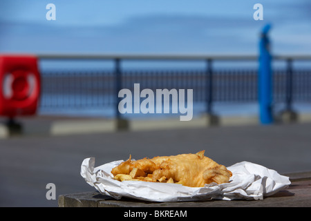 Anglais traditionnel fish and chips dans un papier sur l'enrubanneuse jetée à la mer england uk Banque D'Images