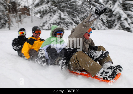 Un groupe d'amis des liens entre faire du traîneau en bas d'une pente dans la station de ski française de Courchevel 1650. Banque D'Images