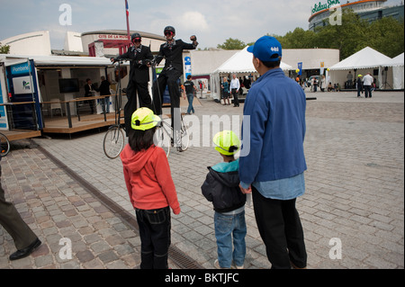 Personnes à vélo dans les parcs, Parc de la Villette, Paris, France, cadre de vélo insolite, vélo d'équitation homme sur pilotis, famille française par derrière, enfants regardant Banque D'Images