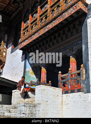 L'homme en costume national assis à l'extérieur entrée temple Trongsa Dzong du Bhoutan Banque D'Images