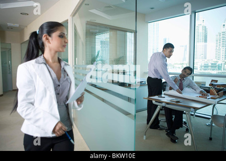 Businesswoman holding document pendant que businessman working in office Banque D'Images