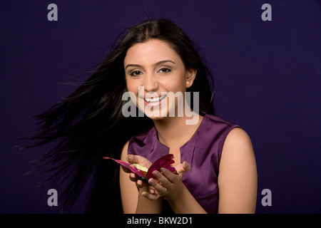 Jeune femme tenant papillon artificiel, smiling, portrait Banque D'Images