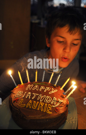 Un garçon de dix ans souffle les bougies sur son gâteau d'anniversaire Banque D'Images