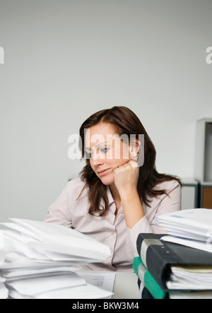 Femme troublée derrière des piles de papier Banque D'Images