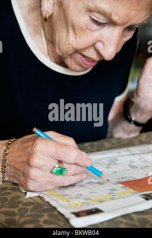 Femme âgée résoudre des mots croisés Banque D'Images