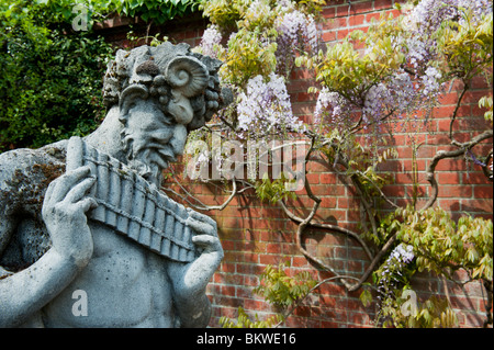 Statue de pan de mur à l'arrière-plan de glycine RHS Wisley Gardens, Surrey, Angleterre Banque D'Images