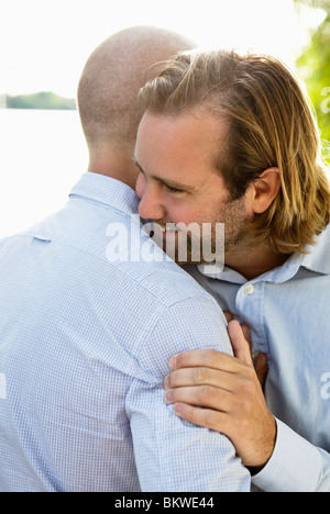 Deux gay men hugging par l'eau Banque D'Images