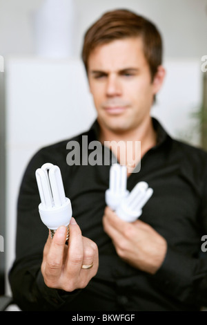 Homme tenant dans les ampoules à basse énergie Banque D'Images