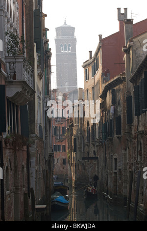 Côté ombragé canal dans le quartier de San Polo avec le campanile de clochettes dans le lointain et gondolier Banque D'Images