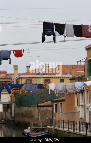 Shirts et autres vêtements enfilés sur lave-ligne à travers un canal latéral à l'Arsenale, sestieri avec bateau amarré à Venise Banque D'Images