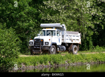 Un livre blanc Mack dump truck camion conduire sur un chemin très étroit canal. Le canal est juste à côté du camion. Banque D'Images