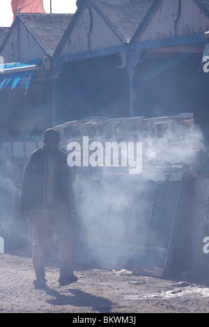 Homme d'âge moyen des promenades dans la fin d'après-midi à travers la fumée de la cuisine de la cale, avec les caisses empilées sur le comptoir Banque D'Images