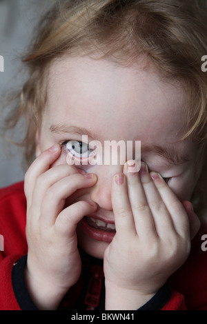 Deux ans enfant bébé fille frotte frotte frotte les yeux fatigués sourire heureux pulling funny face Model publié Banque D'Images