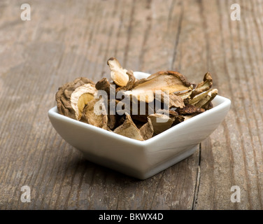 Champignons Porcini séchés dans une assiette blanche sur une table de cuisine rustique Banque D'Images