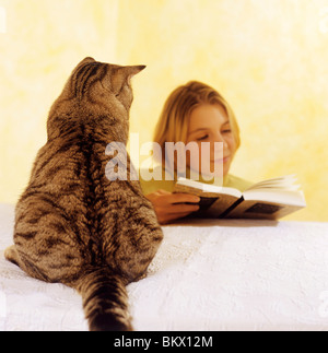 Fille est la lecture d'un livre - chat domestique est à la Banque D'Images