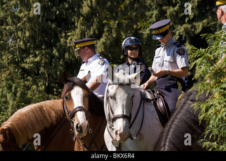 Quatre gendarmes dans le parc Stanley Brown et chevaux gris parmi les arbres Banque D'Images