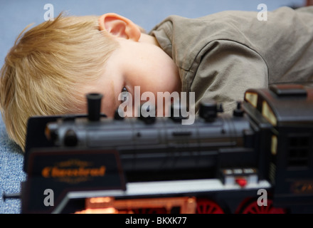 Enfant blonde boy playing with toy locomotive Banque D'Images