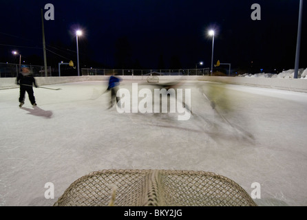 Une famille joue un jeu de pick-up au hockey à l'école élémentaire locale patinoire à Anchorage, Alaska. Banque D'Images