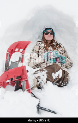 Jeune femme repose dans la neige avec des raquettes sur Milcreek en Canyon, Salt Lake City, Utah. Banque D'Images